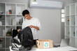 © itchaznong - Person examining a black bag while organizing recyclable materials in a workspace.