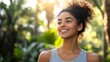 © liliyabatyrova - Basking in the warm sunlight, a young woman with curly hair smiles contentedly, surrounded by vibrant greenery that radiates peace and happiness in the air