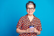 © deagreez - Smiling Mature Woman in Colorful Patterned Shirt Holds a Coffee Cup Against a Bright Blue Background