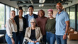 © Eduardo Accorinti - Group of diverse men and women, multiethnic team of businesspeople standing together in office, showing teamwork, inclusion and diversity in workplace with a senior businesswoman in a wheelchair