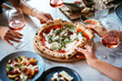 © FornStudio - Friends enjoy a dinner party with pizza and rose wine in a bar or a restaurant.