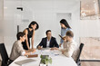 © fizkes - Team bonding. Busy diverse group of multiethnic corporate workers managers executives gather by briefing table for informal conversation training laugh having fun discuss paperwork share experience