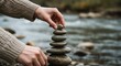 © Neo GT - Hands stacking smooth, flat stones on each other by a river, symbolizing balance and mindfulness.