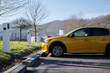 © ADDICTIVE STOCK - Yellow electric car charging at station in a scenic setting
