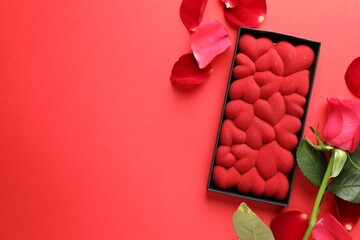 Wall Mural - Chocolate bar decorated with hearts, rose and petals on red background, flat lay. Space for text