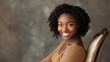 © esp2k - A woman with curly hair is sitting on a chair and smiling