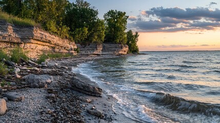 Wall Mural - Serene sunset over a rocky shoreline with gentle waves.