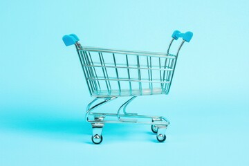 Poster - Shopping Cart Miniature on Light Blue Background Minimalist Concept Retail and Consumerism Commerce