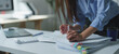 © crizzystudio - Businesswoman organizing a large stack of paperwork with colorful sticky notes, working diligently at her office desk with a laptop and calculator nearby