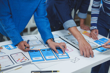 Wall Mural - ui/ux designers collaborating on a new mobile application, arranging various components of the layou