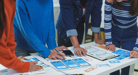Wall Mural - web designers team working on mobile application development analyzing paper prototypes of user inte