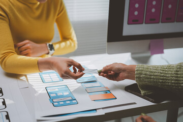 Wall Mural - two ux designers are exchanging a mockup of a mobile app interface during a meeting in the office, d
