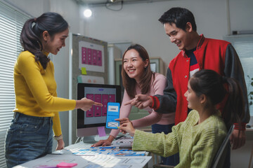 Wall Mural - four asian web designers are discussing about user interface design of a mobile application, compari