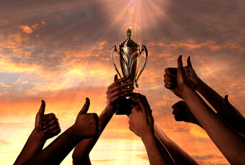 Wall Mural - woman holding golden trophy and people showing thumbs-up against sunset sky, closeup
