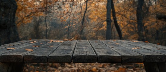 Poster - Rustic wooden table positioned centrally with blurred autumn forest background in warm hues of orange and brown ideal for product display