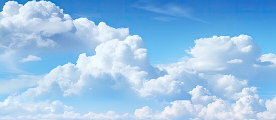 Poster - Fluffy white clouds scattered across a bright blue sky creating a serene and open atmosphere with ample copy space for text or design elements
