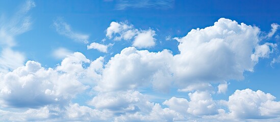 Poster - Vibrant blue sky filled with fluffy white clouds gracefully positioned across the upper half creating ample foreground copy space for text.