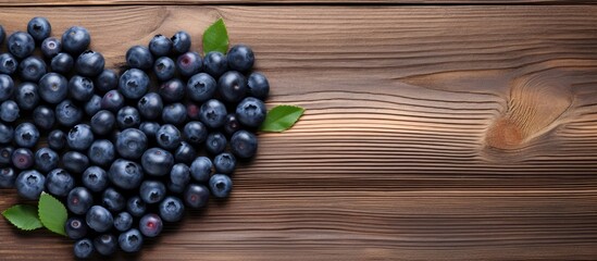 Poster - Heart shape formed by fresh blueberries surrounded by green leaves on a textured wooden table, showcasing dark blue and brown tones.