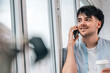 © carballo - young man or student talking on mobile phone at the window