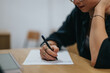 © qunica.com - A student is focused on writing notes at a desk, working on a school assignment. The scene captures concentration, effort, and academic dedication.