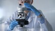 © volha_r - Woman scientist wearing lab coat, white protective gloves and glasses, is using microscope in modern laboratory setup, portrait view. Low key lighting photo. Science and Medicine