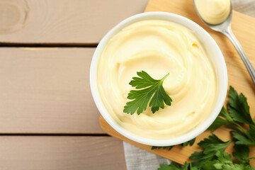 Wall Mural - Delicious mayonnaise sauce with parsley in bowl on wooden table, top view. Space for text