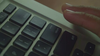 Close-up shot of a finger pressing the return key on a laptop keyboard.
