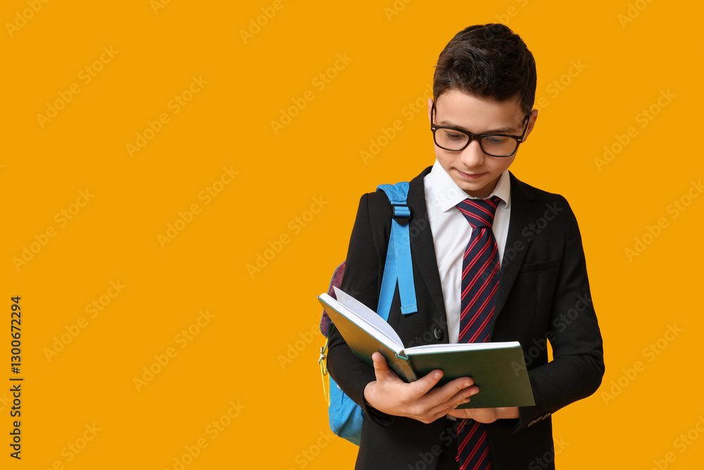 Schoolboy reading book on yellow background
