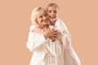 © Pixel-Shot - Happy young woman and her mother in bathrobes hugging on beige background