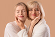 © Pixel-Shot - Happy young woman and her mother in bathrobes hugging on beige background