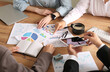 © Pixel-Shot - Business team working with diagrams and tablet during meeting in office, closeup