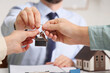 © Pixel-Shot - Real estate agent giving key from house to couple in office, closeup