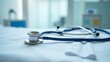 © Vlad - A blue stethoscope rests on a crisp white bedsheet in a bright, modern hospital room.