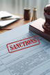 © OM - Document detailing sanctions with a red stamp on a desk with office supplies and an out-of-focus background