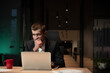 © HudHudPro - Young businessman or startup founder in a suit sits at an office desk, looking concerned while working on a laptop late at night. Concept of workplace stress, decision-making, and business challenges