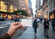© Aminograpix - Hand holding blank business card in a bustling city street at twilight.