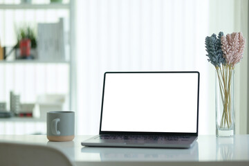 Wall Mural - feminine workspace laptop with blank screen, a coffee cup, and decorative glass vase with flowers.