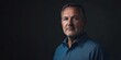 © J. Grayscale - Confident Middle-Aged Man in a Blue Shirt Against a Dark Background