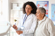 © Pixel-Shot - Female African-American doctor with clipboard and senior patient in clinic