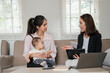 © Satori Studio - Businesswoman consulting a mother holding her baby in a modern living room, highlighting professional advice and family dynamics.