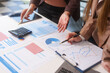 © NanSan - Close-up of two businesswomen working at desk discussing business strategies, analyzing financial charts, planning marketing plans and using laptop to drive business growth in professional office
