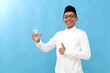© ArvStd - Asian muslim man showing thumbs up while holding a glass of water