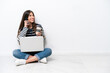 © luismolinero - Young caucasian woman with a laptop sitting on the floor isolated on white background holding coffee to take away and a mobile