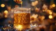© Aisha - Honey drizzling from a spoon into a glass, with a bee-themed background softly blurred