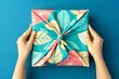 © Metthaisonk - Hands holding a colorful fabric wrapped gift on a blue background.
