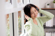 © NT_studio - Portrait happy young woman wearing headphones listening music while standing with fun and enjoy in the living room at home, happiness female with entertainment, one person, lifestyle concept.