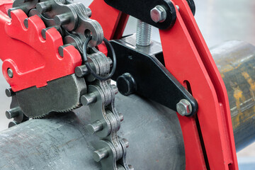 Aufkleber - A red and black tool is used to cut a chain. The chain is attached to a pipe industrial service concept background