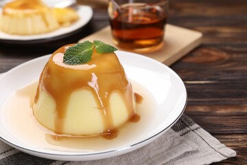 Wall Mural - delicious pudding with caramel sauce and mint on wooden table, closeup