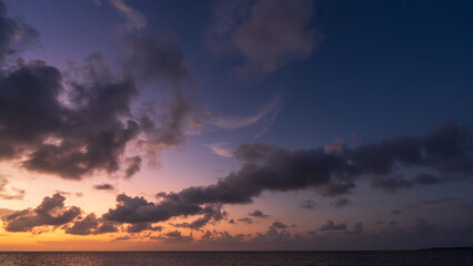 Wall Mural - dusk sky over sea, sunset sky clouds in the evening with golden orange sunlight and dark blue hour o