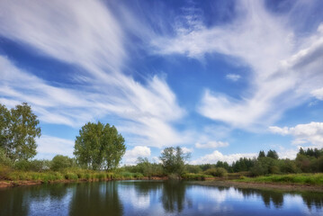 Wall Mural - the landscape features a cloudy sky above a picturesque river.
